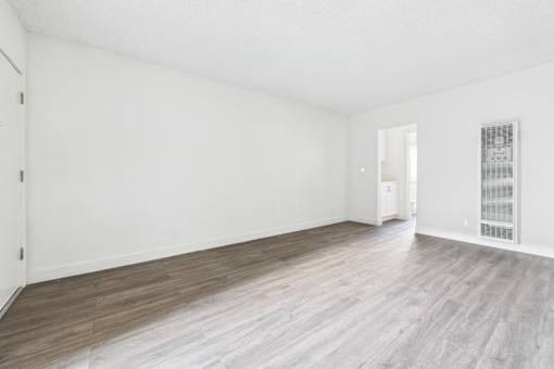 A room with wooden flooring and white walls.