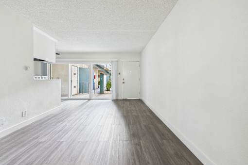 A long, empty hallway with wood flooring and white walls.