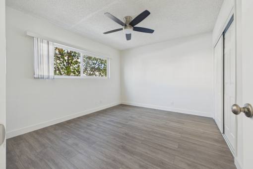 A room with a ceiling fan and a window with white curtains.