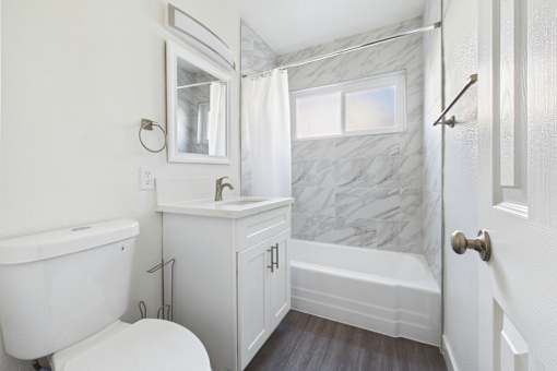 A white bathroom with a marble shower wall.