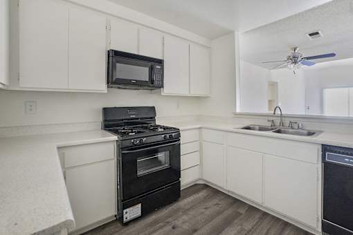 A kitchen with black appliances and white cabinets.