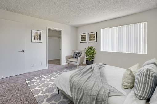 A bedroom with a bed, chair, and two pictures on the wall.