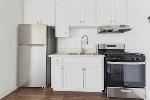 A kitchen with white cabinets and a stainless steel refrigerator.