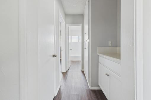 A long hallway with white walls and wood floors.