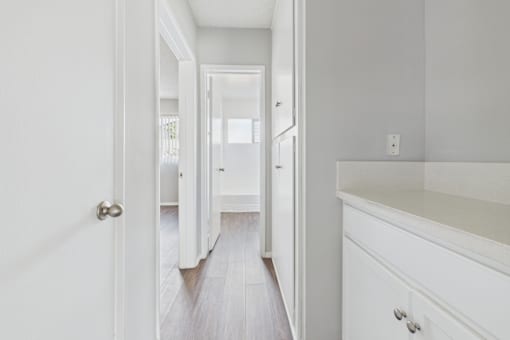 A white hallway with a wooden floor and white walls.