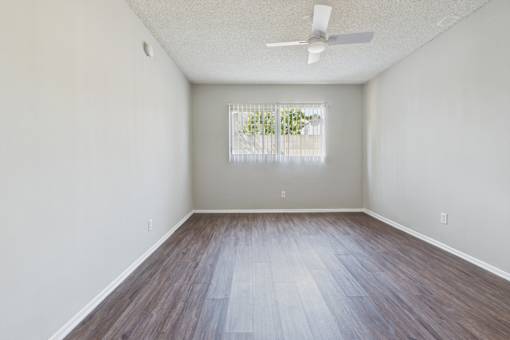 A room with a ceiling fan and a window with blinds.