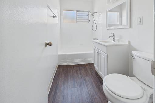 A white bathroom with a toilet, sink, and mirror.