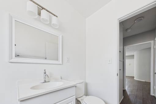 A white bathroom with a toilet, sink, and mirror.
