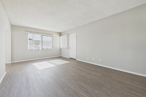 Empty room with light wood flooring and white walls.