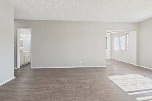 A spacious room with wooden flooring and white walls.