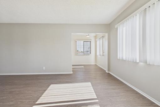 A room with a white mat on the floor and a window with white curtains.