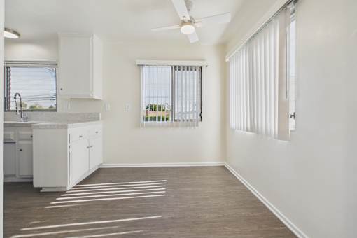 A kitchen with white cabinets and a window with blinds.