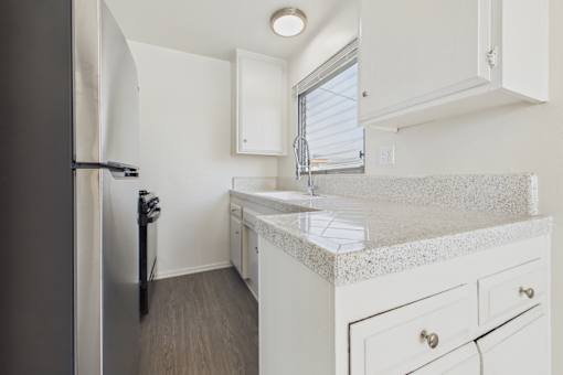 A kitchen with a refrigerator, sink, and cabinets.