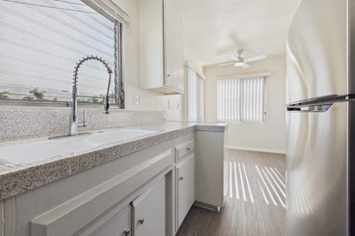 A kitchen with a granite countertop and a stainless steel refrigerator.