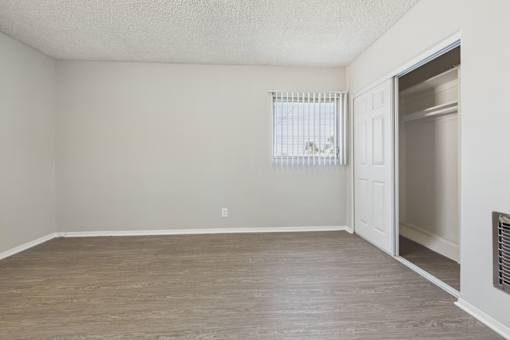 A room with a wooden floor and a window with blinds.