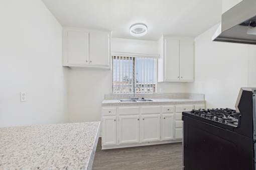A kitchen with white cabinets and a black stove top oven.