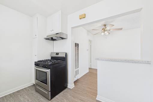 A black stove in a white kitchen with a fan on the ceiling.
