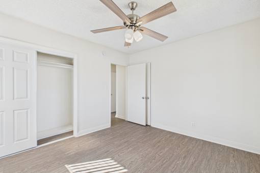 A room with a ceiling fan and a rug on the floor.