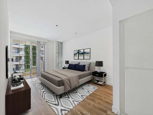 A bedroom with a large bed and a balcony with a view of a building.