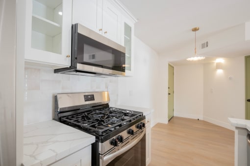 a kitchen with white cabinets and a stove and a microwave