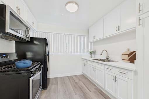 A kitchen with black appliances and white cabinets.