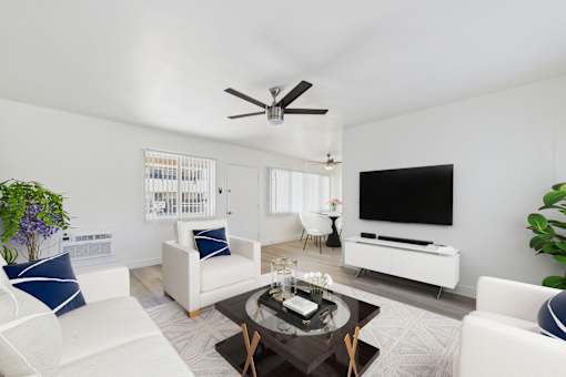 A living room with a white sofa, a coffee table, and a television.