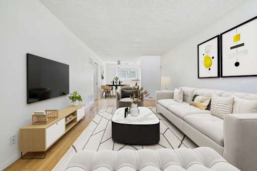 A modern living room with a white couch, a black coffee table, and a flat-screen TV mounted on the wall.