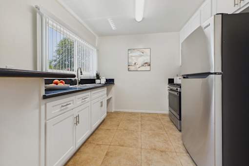 A kitchen with white cabinets and a black countertop.
