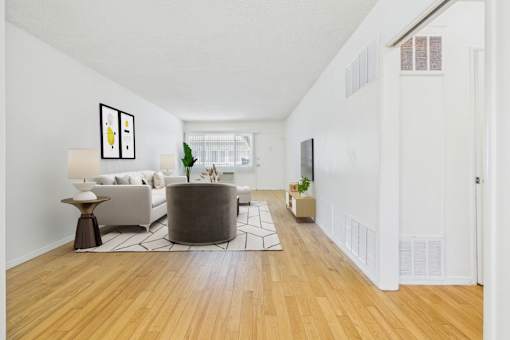 A living room with a white couch and a grey ottoman.
