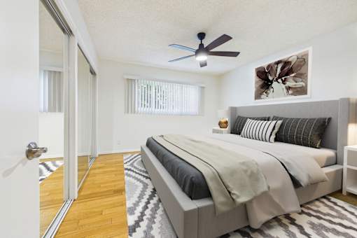 A bedroom with a large bed and a ceiling fan.