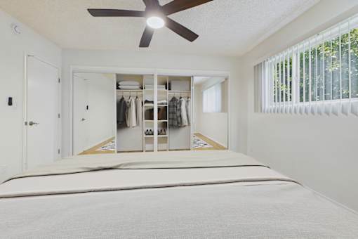 A bedroom with a large bed and a closet with clothes hanging.