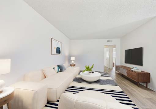 A living room with a white couch, a white coffee table, and a black and white striped rug.