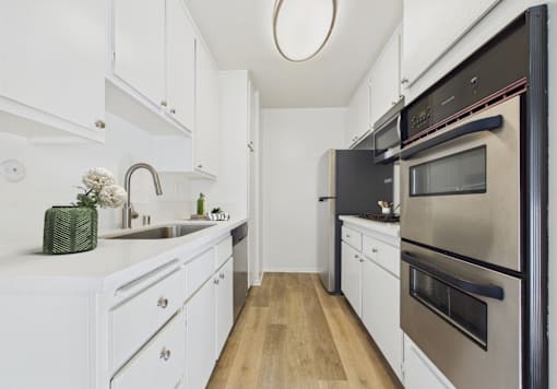 A modern kitchen with white cabinets and stainless steel appliances.