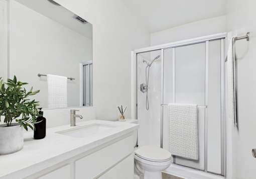 A white bathroom with a toilet, sink, and shower.