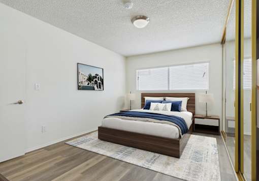 A bedroom with a bed, nightstand, and a picture on the wall.