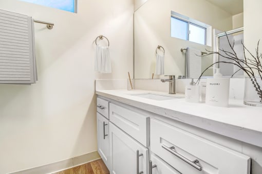 a bathroom with white cabinets and a sink and a mirror