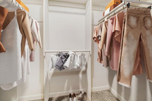 a closet with clothes hanging on a rack and a white closet door