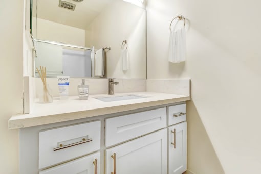 a bathroom with white cabinets and a sink and a mirror