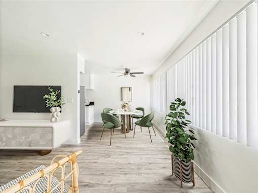 A living room with a white sofa, a green chair, a wooden table, and a potted plant.