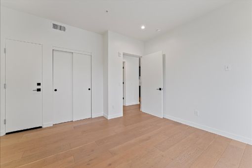 A room with white walls and wooden flooring with three doors.