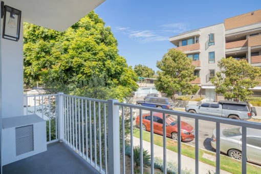 the view from the balcony of an apartment building with cars parked on the street