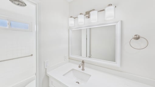 A white bathroom with a sink and mirror.