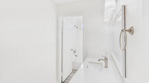 A white bathroom with a sink and mirror.