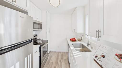 A modern kitchen with white cabinets and stainless steel appliances.
