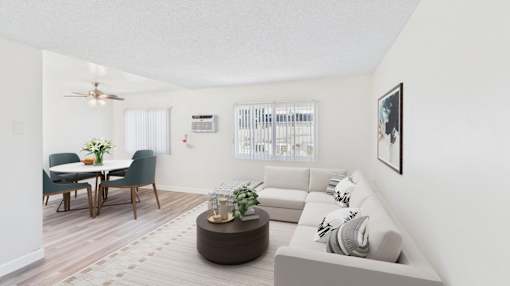 A living room with a couch, a dining table, and a ceiling fan.
