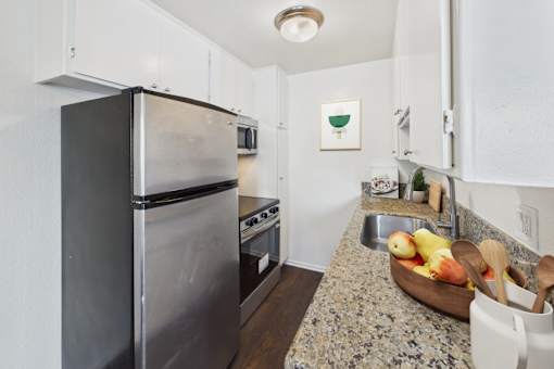 A kitchen with a granite countertop and a black refrigerator.