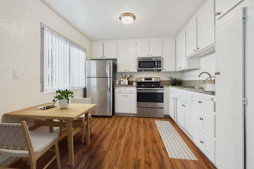 A kitchen with white cabinets and a wooden table.