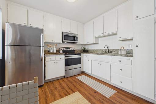A kitchen with white cabinets and a stainless steel refrigerator.