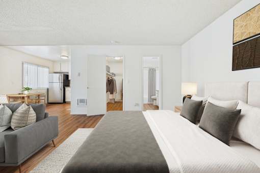 A bedroom with a large bed and a grey couch.