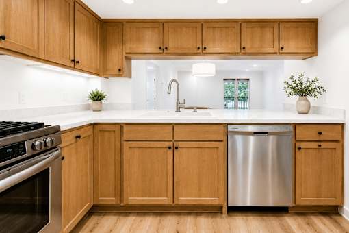 A kitchen with wooden cabinets and a stainless steel dishwasher.